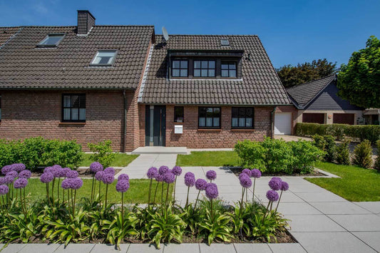 Beautiful home featuring Metten ARCADIA® Cosi concrete patio complemented by vibrant flowers in the garden.