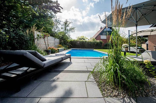 Terrassenplatte METTEN ARCADIA® Torino umgeben von Grün mit Schwimmbad und Gartenmöbeln für eine moderne Außenanlage.