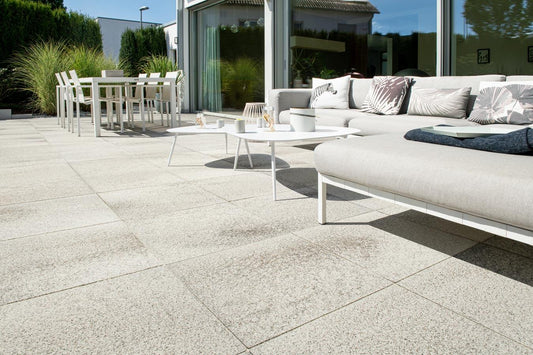 Terrassenplatte METTEN UMBRIANO Quarzbeige auf einer modernen Terrasse mit Lounge-Garnitur und Esstisch.