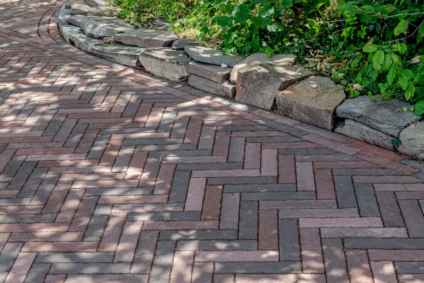 Pflastersteine METTEN SPRING ALVAR Rotschwarz in Herringbone-Muster entlang einer geschwungenen Ecke.