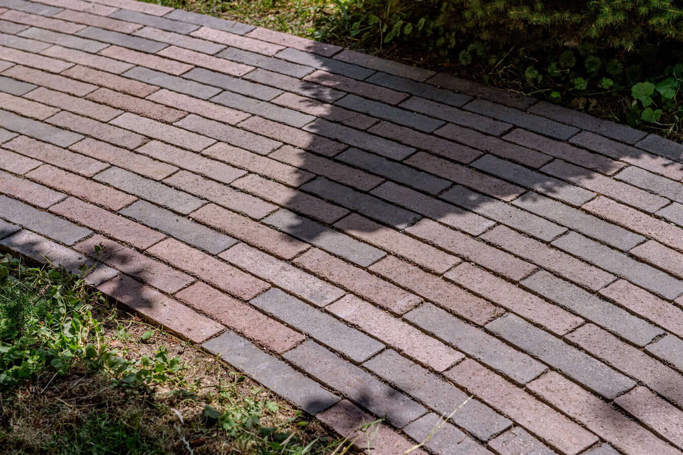 Pflastersteine METTEN SPRING ALVAR Rotschwarz auf einem gepflasterten Gehweg im Sonnenlicht