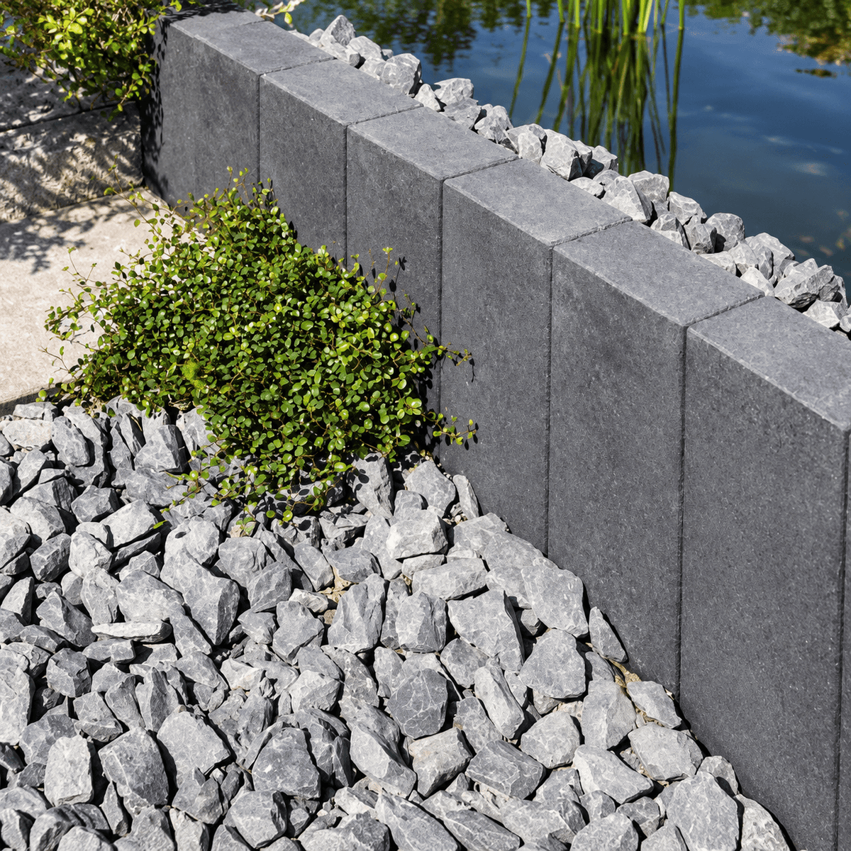 Jasto TRENDLINE Palisaden anthrazit mit dekorativen Steinen und Pflanzen im Gartenbereich