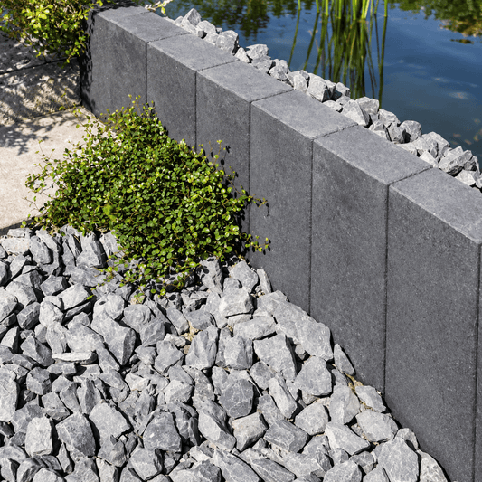 Jasto TRENDLINE Palisaden anthrazit mit dekorativen Steinen und Pflanzen im Gartenbereich