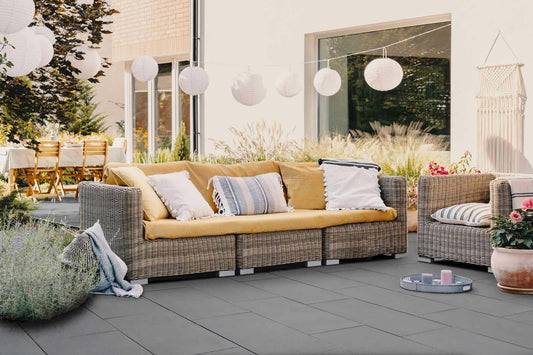 Terrassenplatte METTEN SPRING TADAO Dunkelgrau auf gemütlicher Terrasse mit bequemen Möbeln und schöner Beleuchtung.