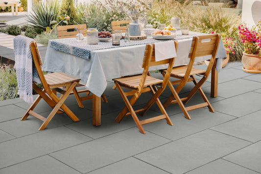 Terrassenplatte METTEN SPRING TADAO Mittelgrau unter einem Esstisch im Freien mit Stühlen.
