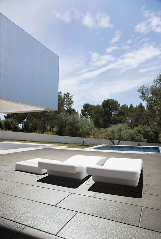 Terrassenplatte METTEN SPRING SORENO Schiefergrau auf einer modernen Terrasse mit weißen Liegen.