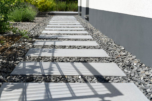 Terrassenplatte METTEN SPRING SORENO Granithell, helle Betonplatten auf Kiesweg im Garten.