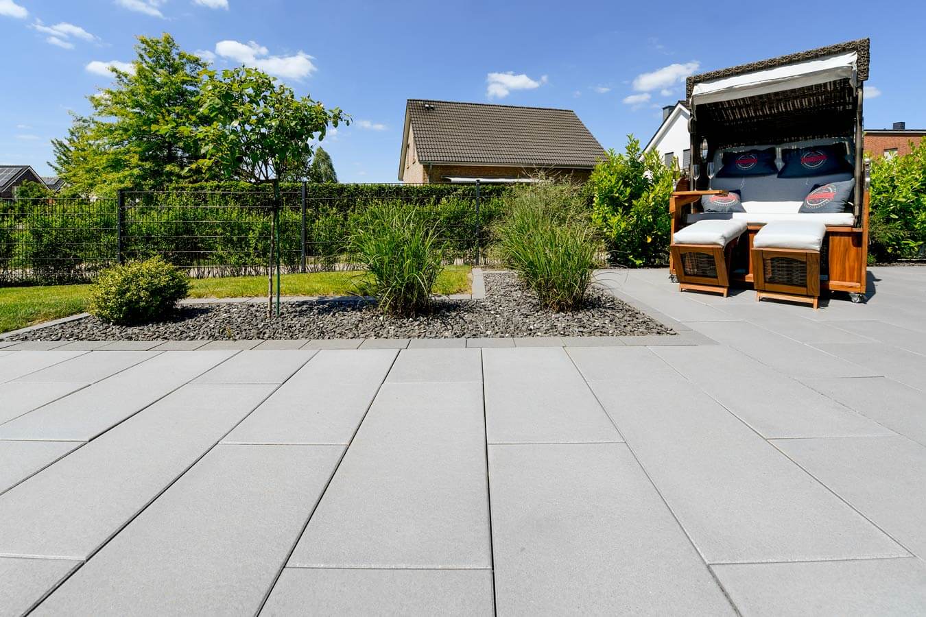 Terrassenplatte METTEN SPRING SORENO Granithell in einem modernen Garten mit Sonnenliege und Pflanzen.