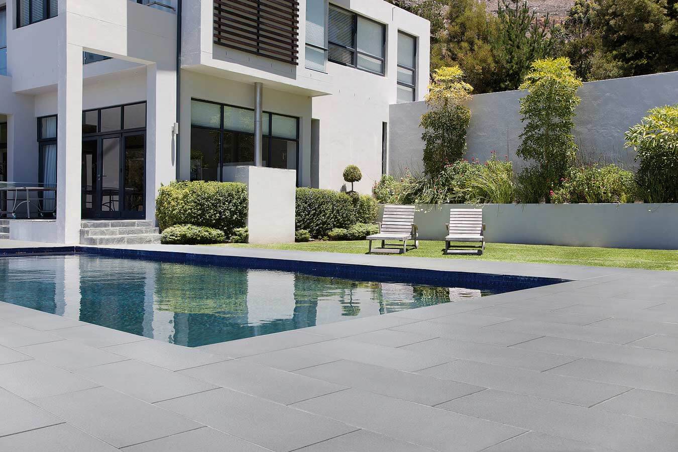 Terrassenplatte METTEN SPRING SORENO Maggiagrau in moderner Poollandschaft mit eleganter Architektur.