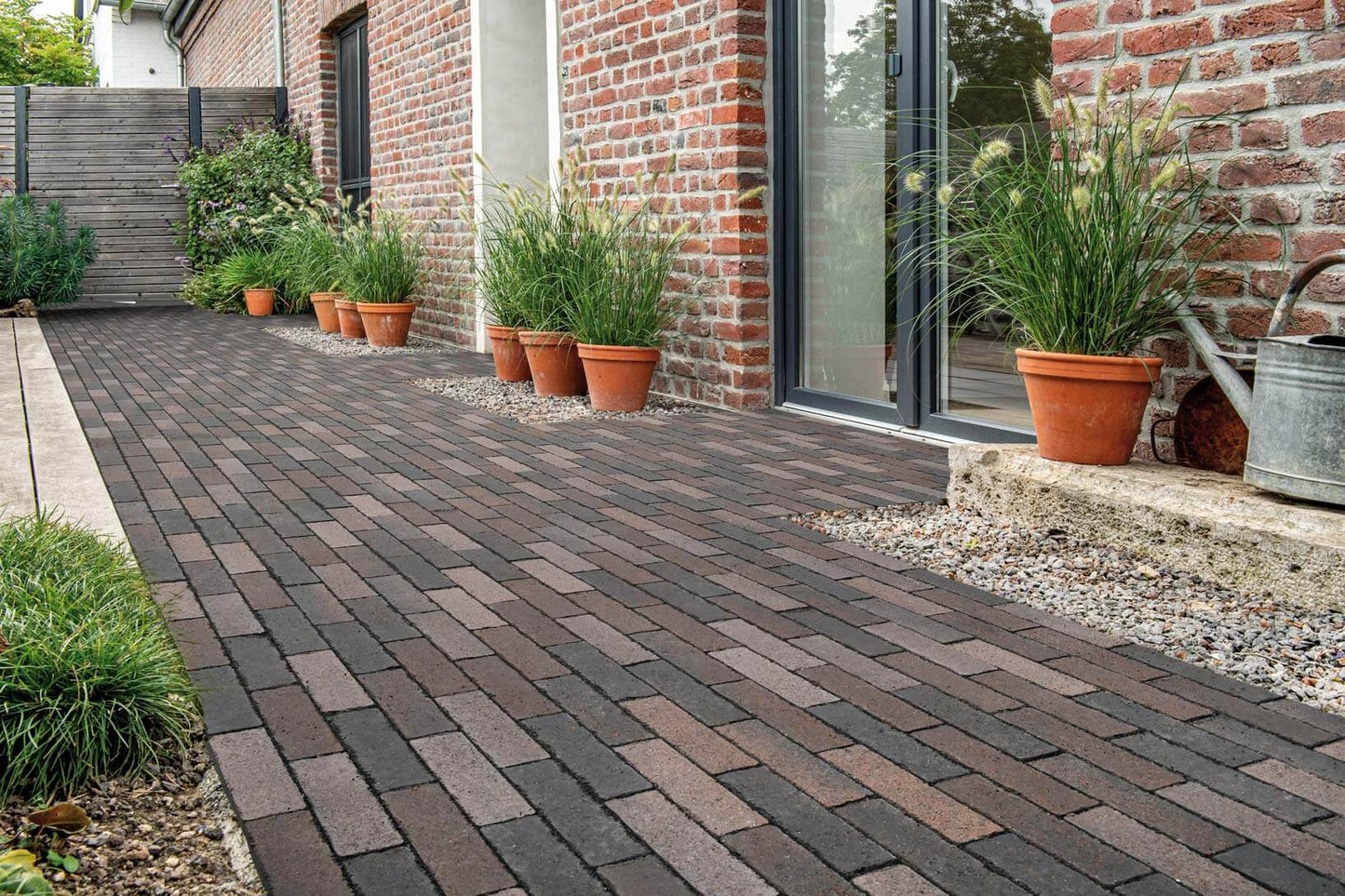 Pflastersteine METTEN SPRING ALVAR Rotschwarz in einem stilvollen Gartenbereich mit Pflanzgefäßen.