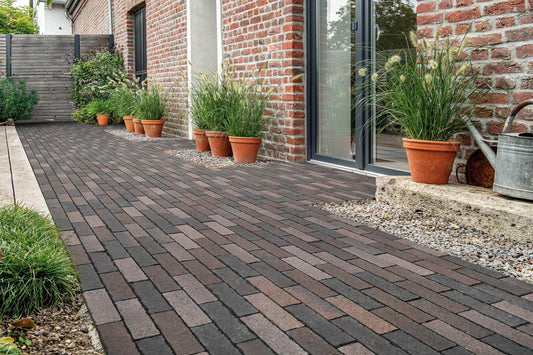 Pflastersteine METTEN SPRING ALVAR Rotschwarz in einem stilvollen Gartenbereich mit Pflanzgefäßen.