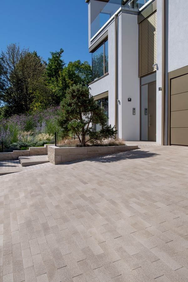 Terrassenplatte METTEN UMBRIANO Granitbeige auf einem modernen Außenbereich mit Pflanzen.