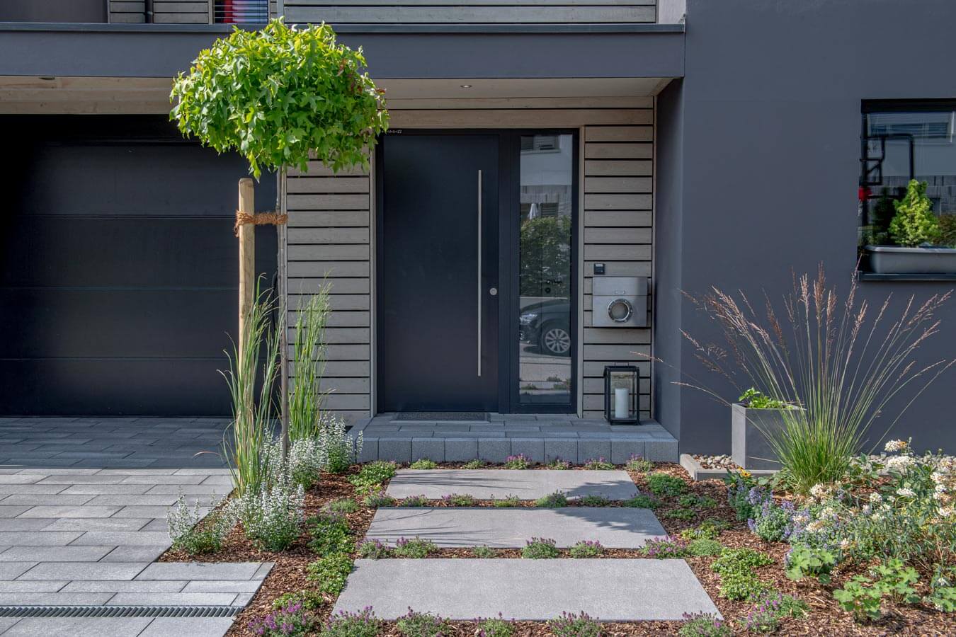 Pflastersteine METTEN UMBRIANO Platingrau im modernen Eingangsbereich mit Garten und Eingangstür.