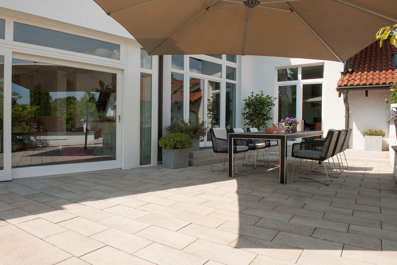 Terrassenplatte METTEN UMBRIANO Granitbeige auf einer modernen Terrasse mit Tisch und Stühlen.