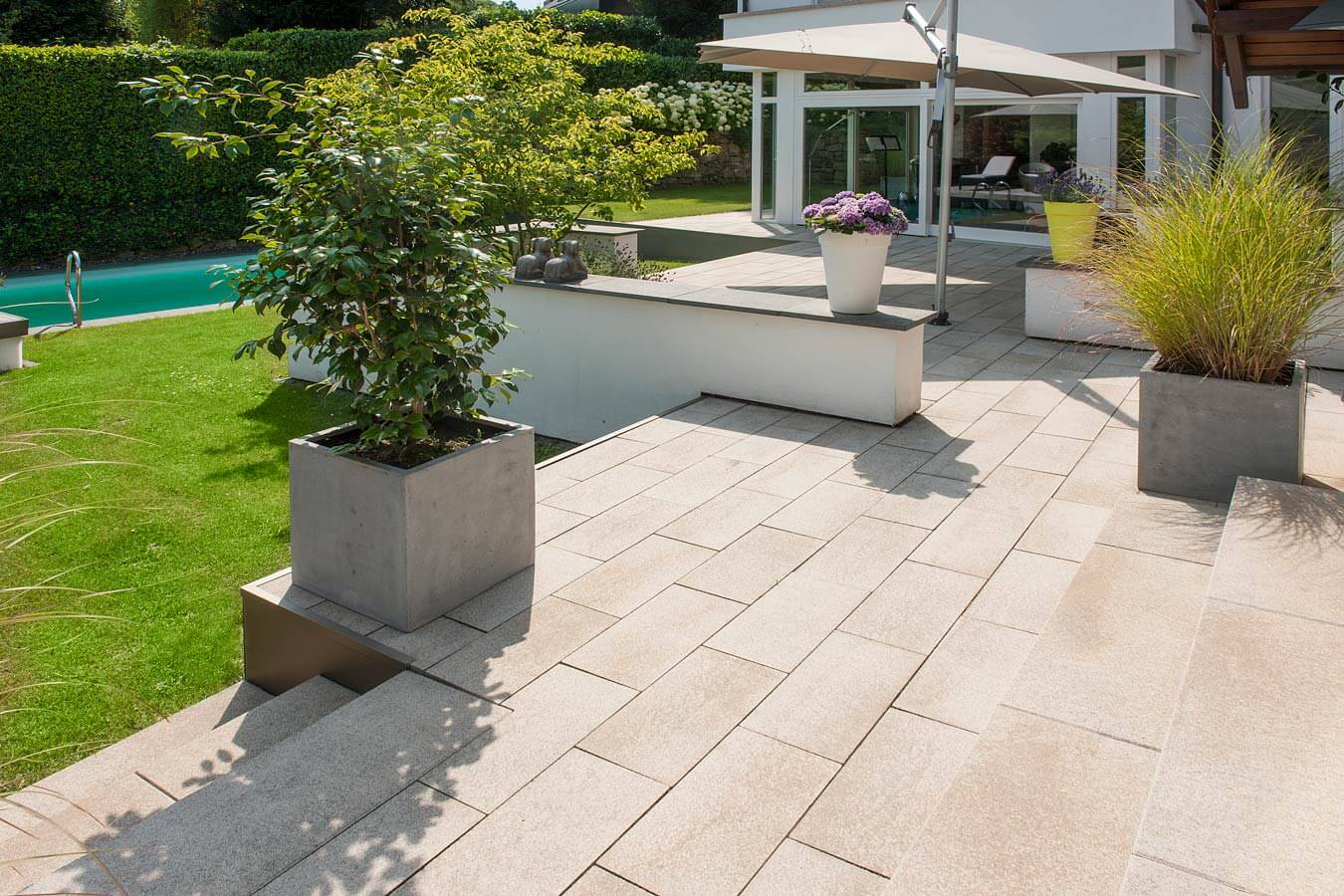 Terrassenplatte METTEN UMBRIANO Granitbeige auf einer modernen Terrasse mit Pflanzen und Pool