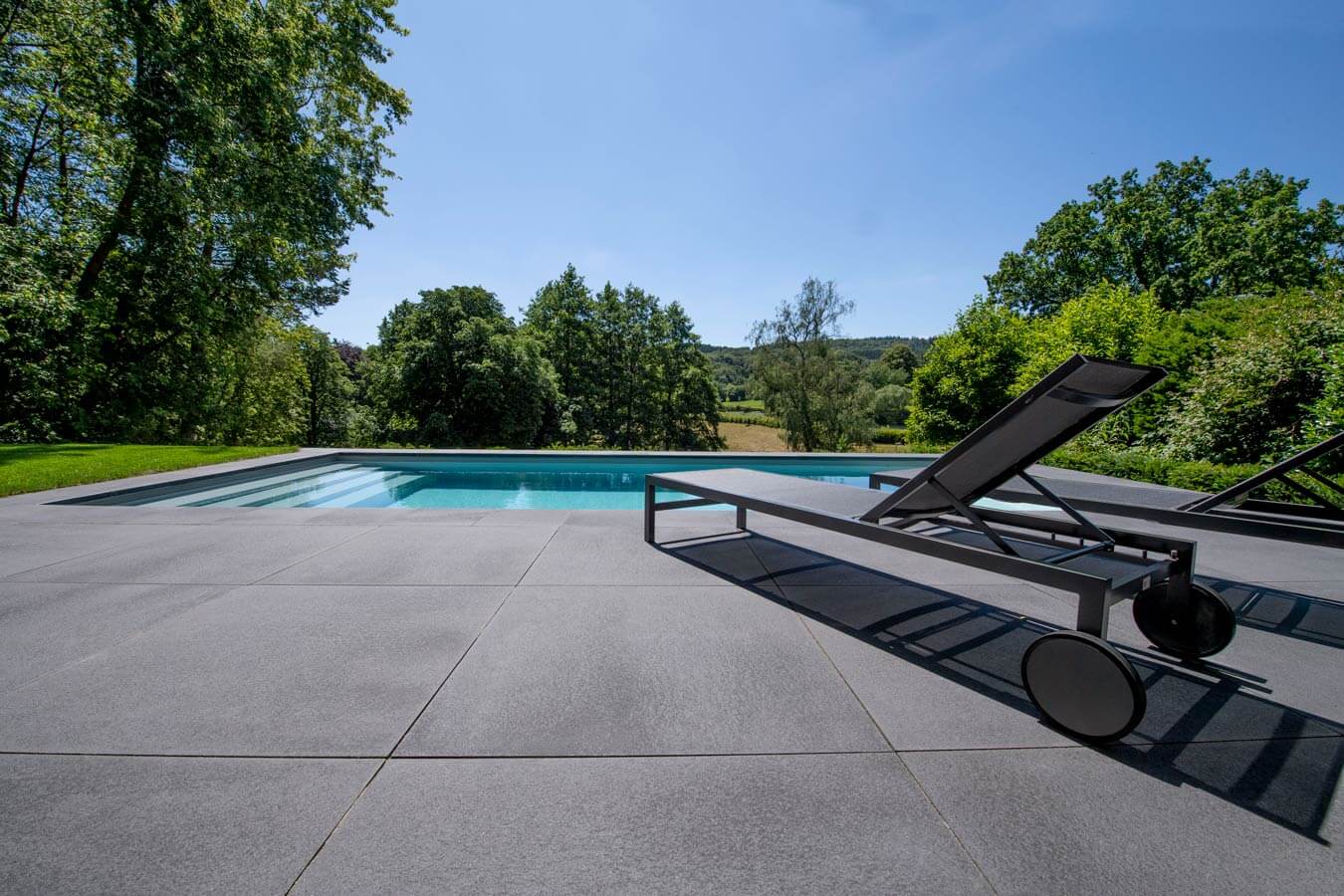 Pflastersteine METTEN UMBRIANO Grauanthrazit um Pool mit Sonnenliege auf grünem Grundstück