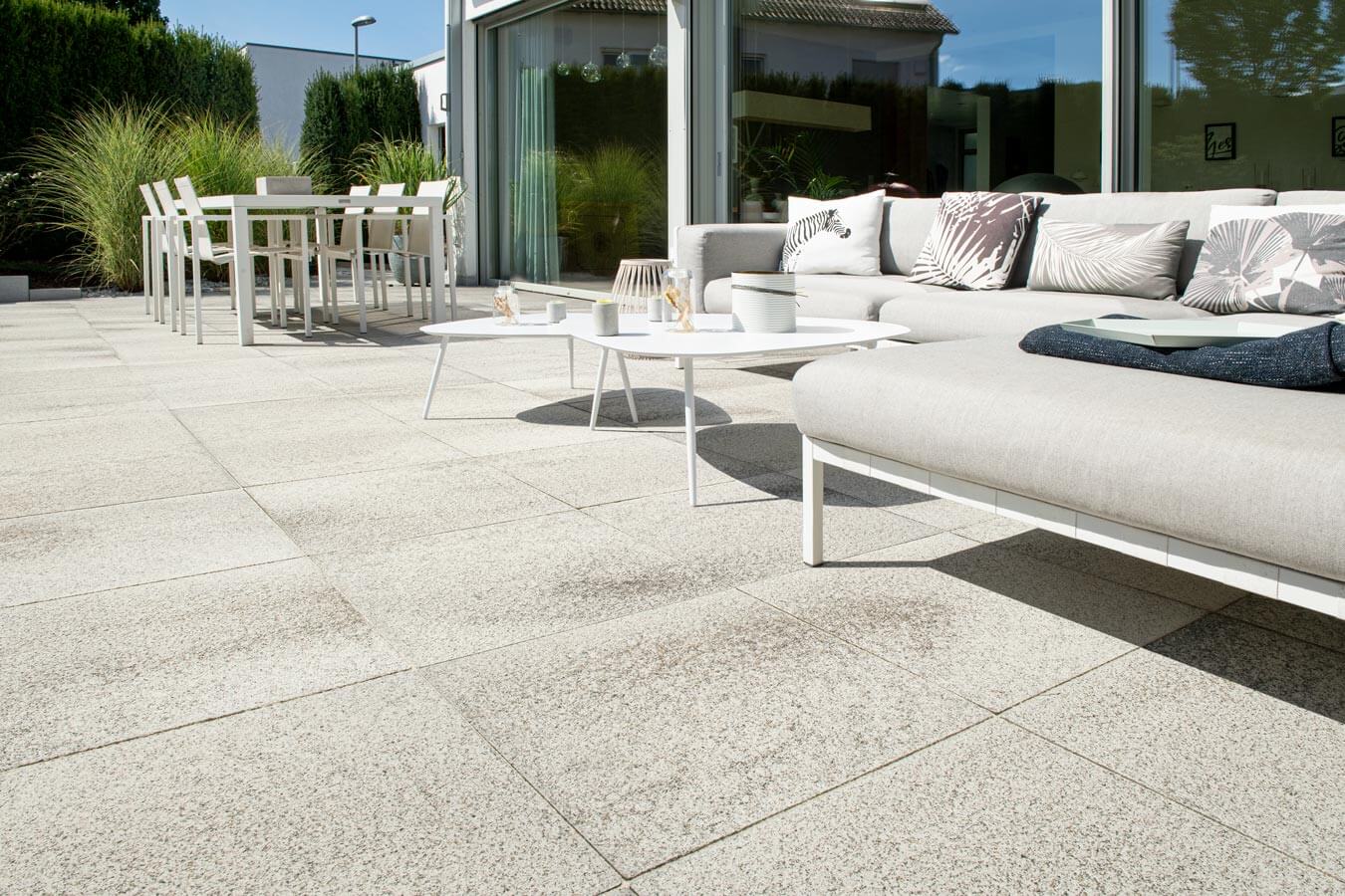 Terrassenplatte METTEN UMBRIANO Quarzbeige auf einer modernen Terrasse mit Lounge-Garnitur und Esstisch.