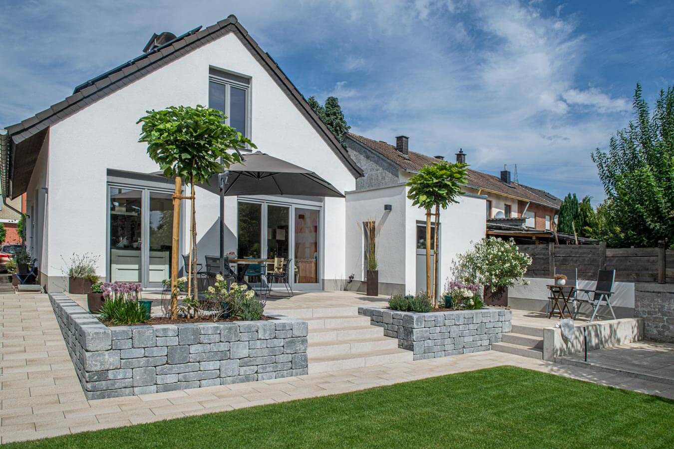 Terrassenplatte METTEN UMBRIANO Granitbeige auf einer modernen Terrasse mit Garten.